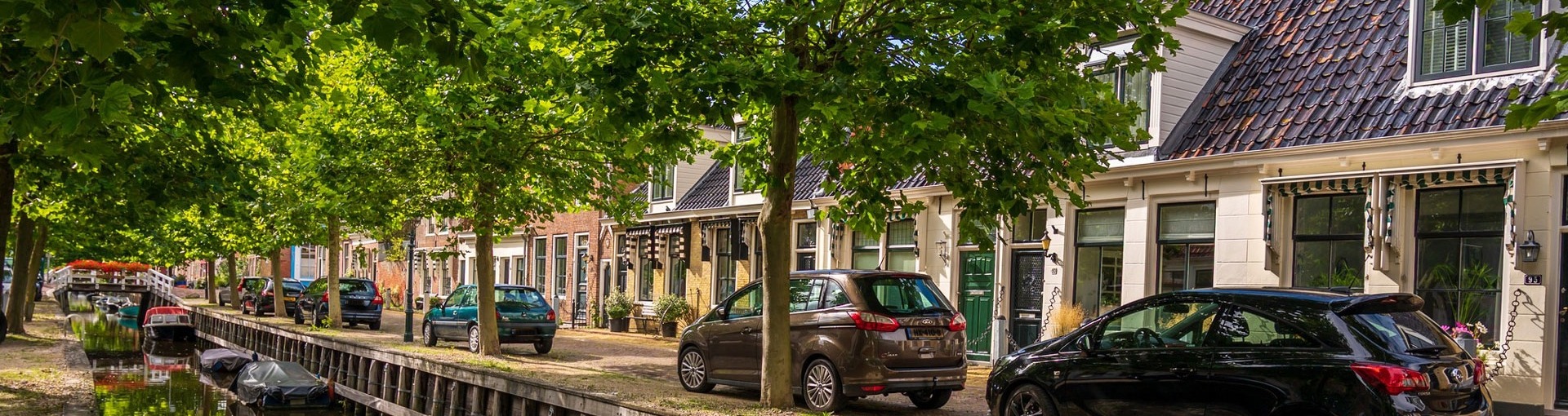 Een straat in Harlingen met huizen en een bootje in de gracht